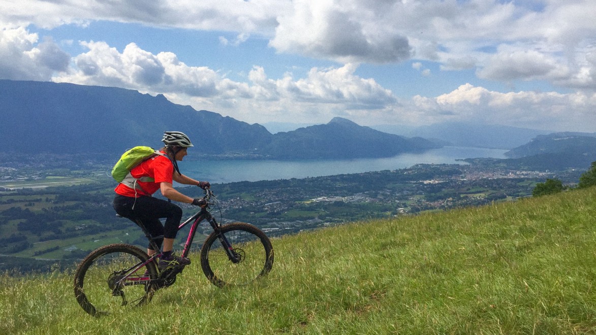 Mountainbiker in der Auffahrt vor dem Hintergrund des Lac du Bourget und der Montagne de l'Epine