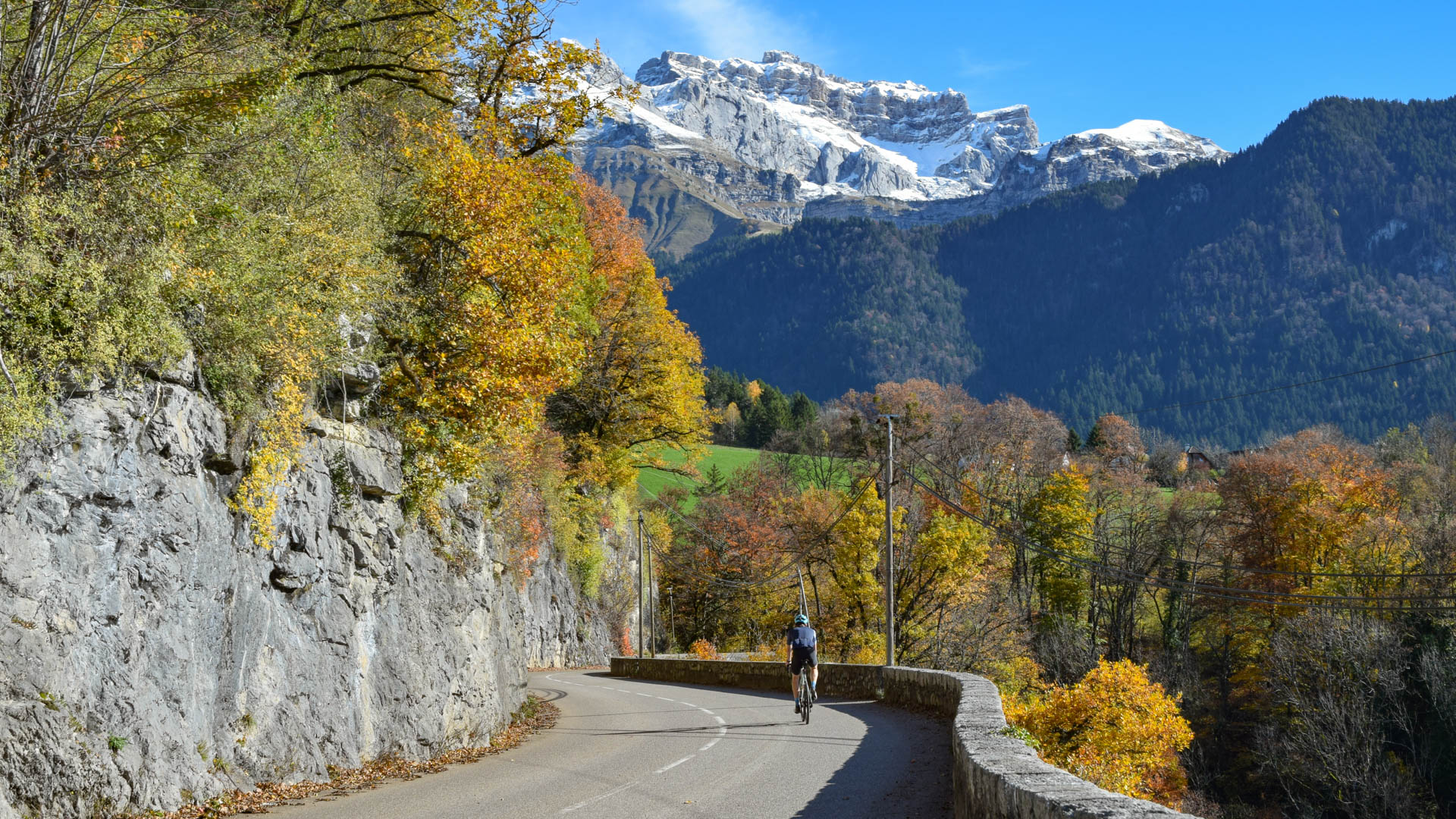 Ein Rennradfahrer fährt die Straße zum Col de la Forclaz hinauf, im Hintergrund die Tournette.