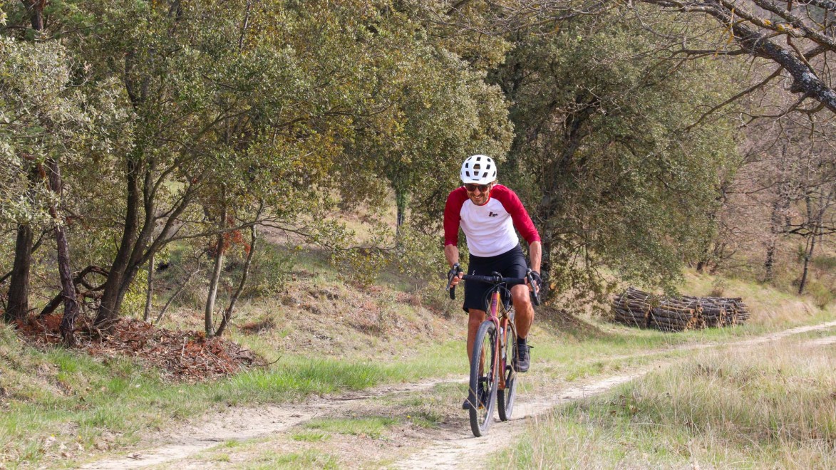 Ein Gravelbike-Fahrer auf einer schönen Piste inmitten von Steineichen.