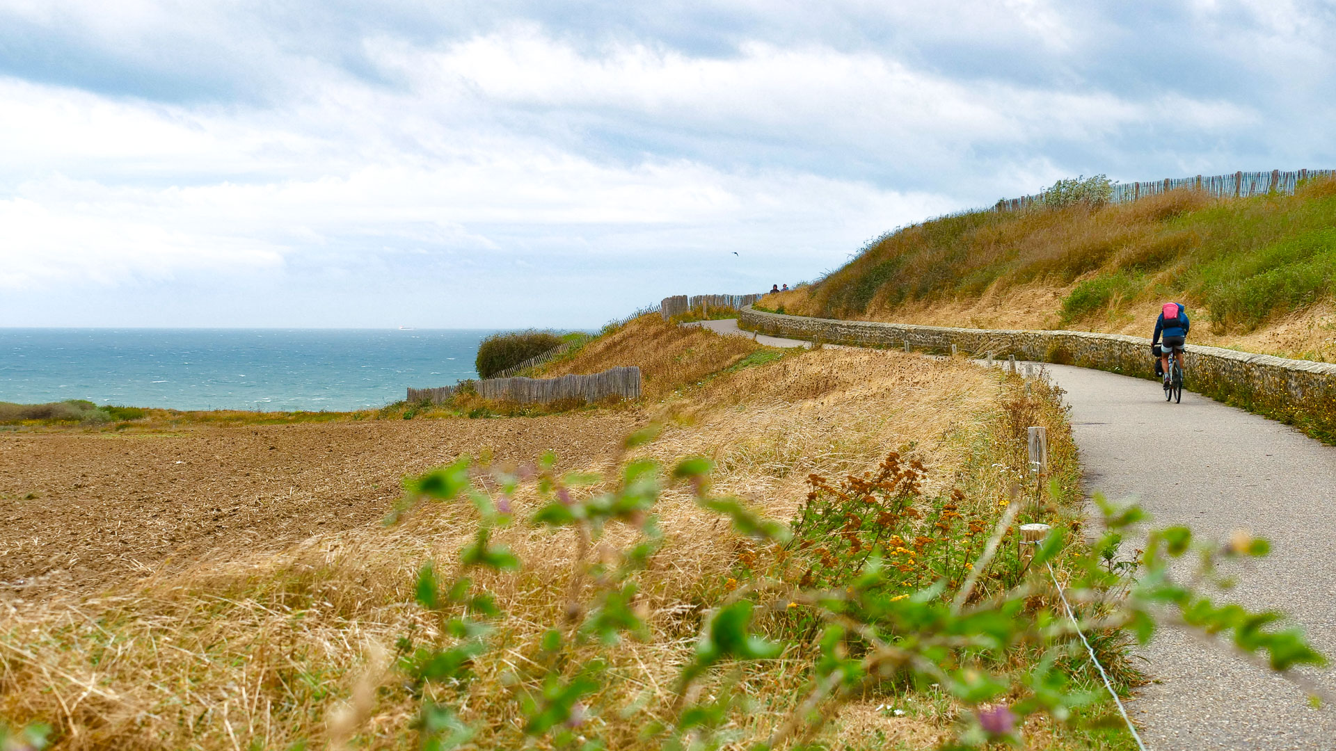 Ein Radfahrer auf einem Radweg entlang der felsigen Opalküste.