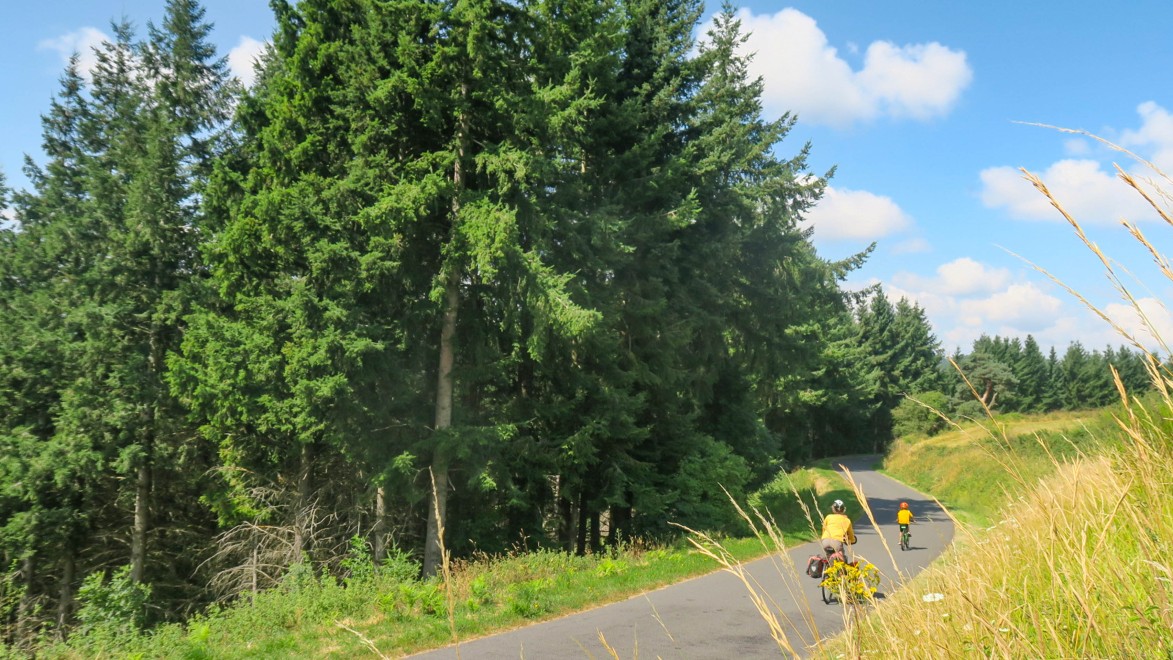 Radfahrerin mit einem Kind auf einer einsamen Landstrasse im Allier.