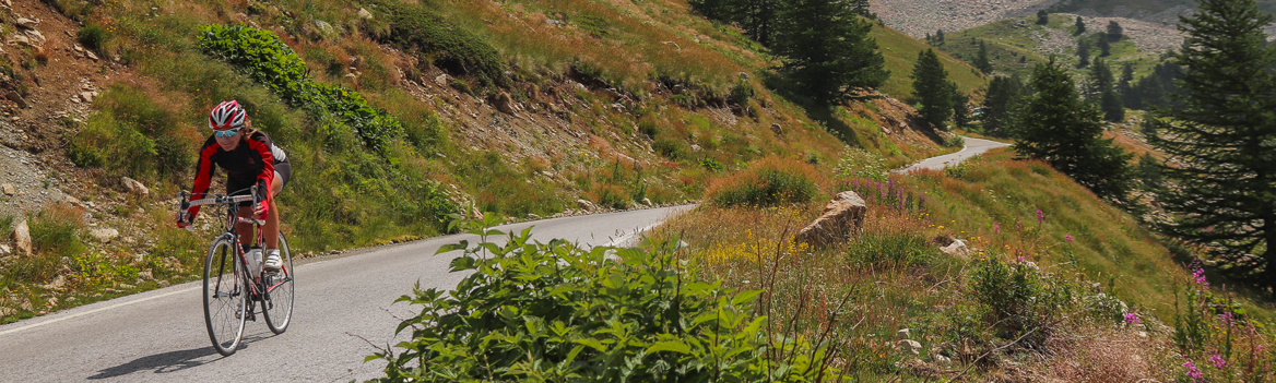 Rennradfahrerin in der Abfahrt vom Col de la Lombarde in den Südalpen