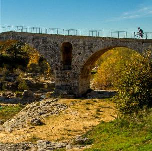 Rennradfahrer auf einer Steinbrücke